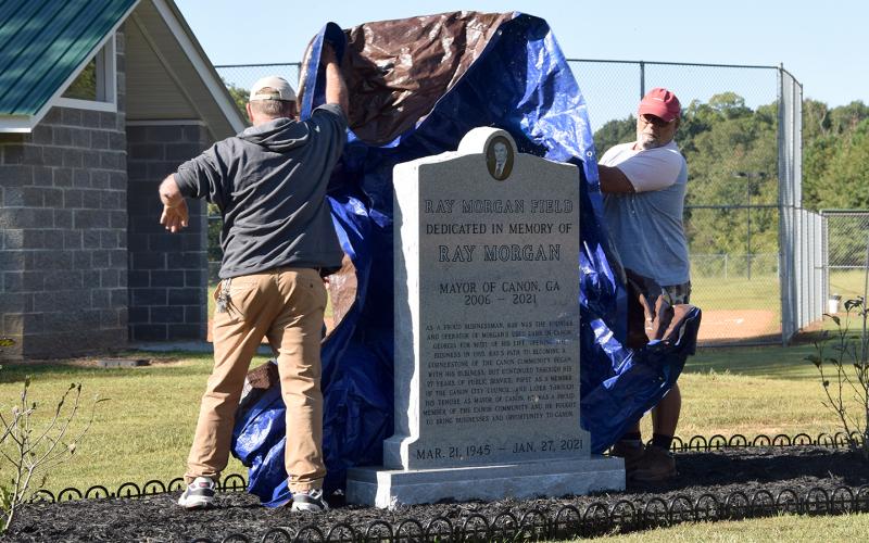 Canon city employees Kyle Parris, Terry Whitworth and Justin Henderson unveil a monument honoring Ray Morgan at the new Ray Morgan Field. (Photo by Sinclair)