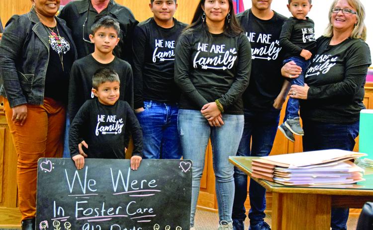 Steve and Angela Whidby completed the adoption Thursday of six siblings who had been in foster care with the family since 2017. Pictured in the courtroom at the Franklin County Courthouse are (front) Angel (holding sign) Felipe, (back) Case Manager Stephanie Tate, Steve Whidby, Edwin, Jennifer, Jose, Emmanuel and Angela Whidby. It was the largest single adoption in county history. (Photo by Scoggins)
