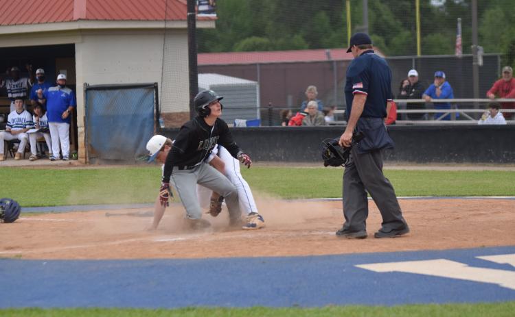 Evan Herring looks to the umpire just moments before being ruled safe on a play at the plate Friday against Oconee County in Watkinsville. (Photo by Scoggins)