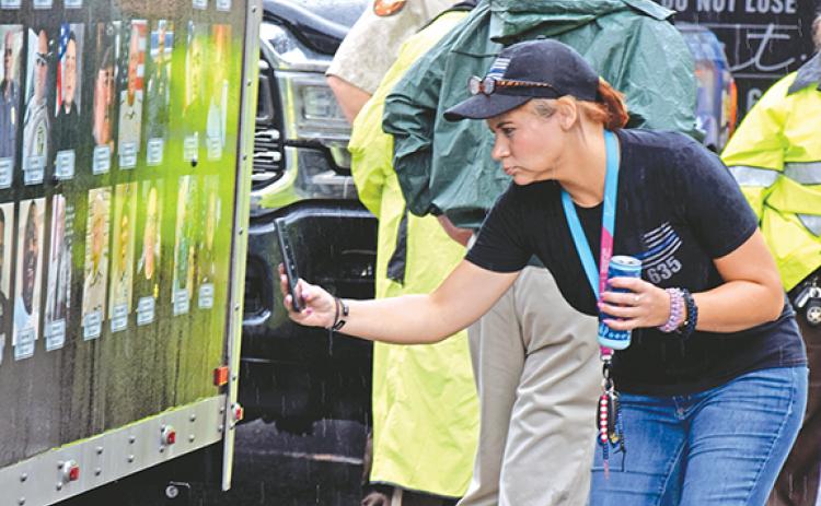 Jennifer Garner, widow of Franklin County Sheriff’s Deputy William “Bill” Garner, takes a photo of her late husband’s picture on the side of the Beyond the Call of Duty Ride to Remember trailer, which depicts photos of all law enforcement officers who died in 2020. (Photo by Scoggins)