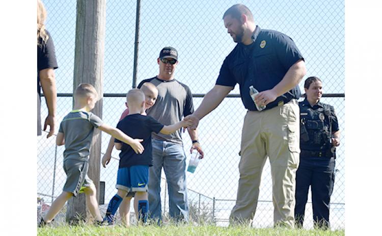 Maverick Fuller, with his brothers Arie and Tyson, shakes Lavonia Officer Michael Herring’s hand, as their father Roger Fuller watches. (Photo by Sinclair)