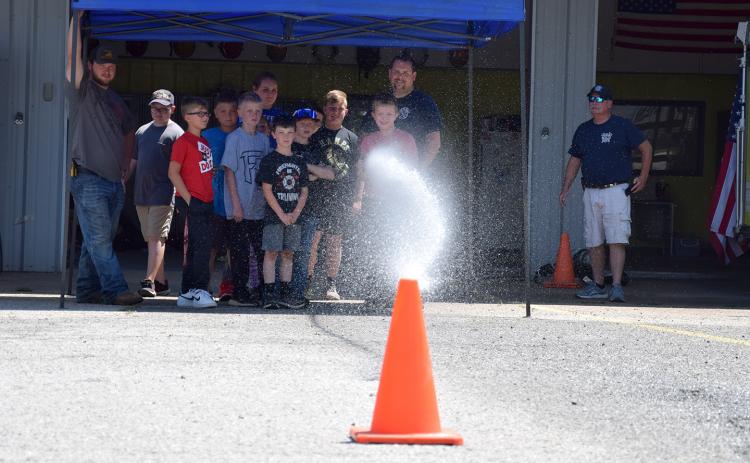 Mitchell Thurmond attempts to knock over a cone while using a fire hose during Junior Firefighter Day last week at the Carnesville Fire Department. (Photo by Sinclair)