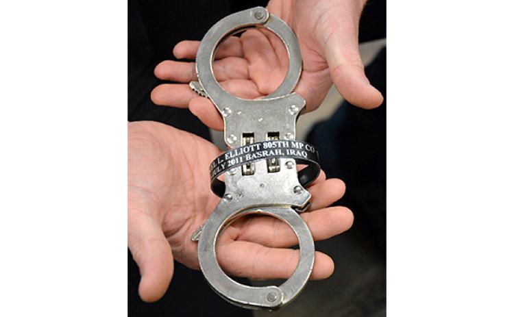A pair of handcuffs owned by Jonathan Merck that were owned by a friend who was killed in Iraq were used to secure Gabrielle Beutler after she was arrested on charges of making up her veteran status and other charges. Merck wears a bracelet with the name of his friend, SPC Daniel Lucas Elliott.