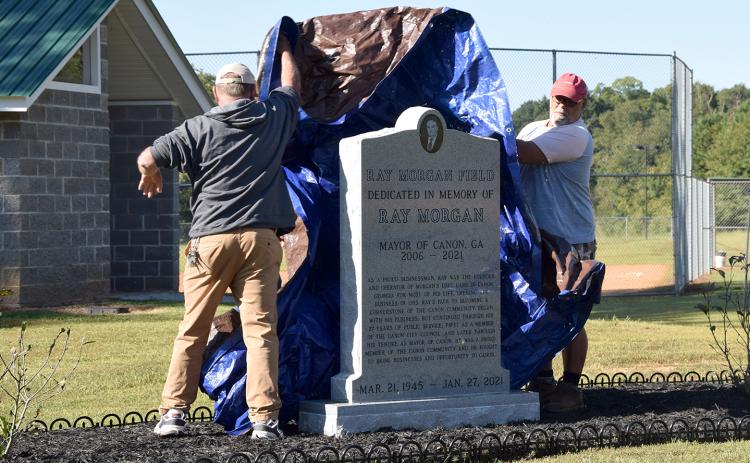 Canon city employees Kyle Parris, Terry Whitworth and Justin Henderson unveil a monument honoring Ray Morgan at the new Ray Morgan Field. (Photo by Sinclair)
