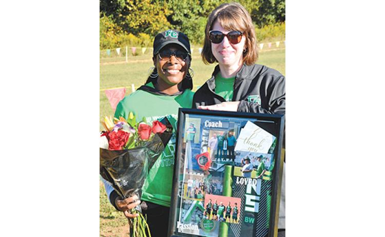 Assistant Coach Ann Bowman presents Heather Woods with a shadow box honoring late Coach Bill “Woody” Woods Saturday during the Pridelands Invitational. (Photo by Scoggins)