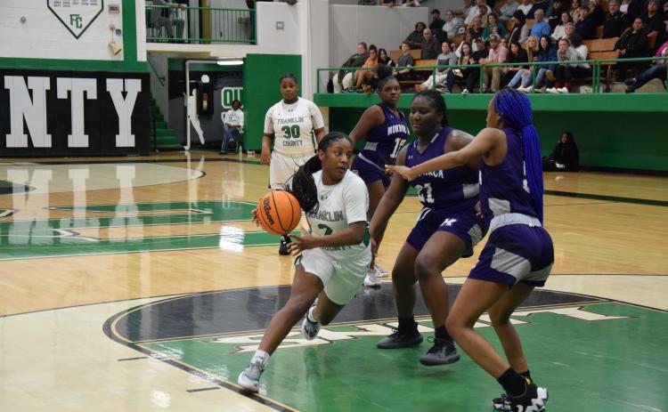 Paris Gaye drives by two Monroe defenders Tuesday in action at the Lion’s Den. Gaye had 23 points to lead the Lady Lions to a win.