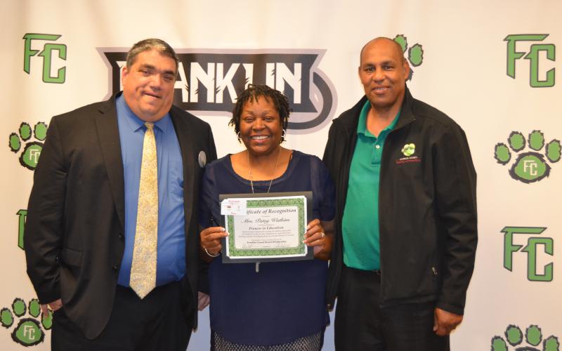 Patsy Watkins (center) was joined by husband Ken (right) while being honored last week by Franklin County School Superintendent Chris Forrer (left) and the board of education for being named a Pioneer in Education by Pioneer RESA. (Photo by Eberhardt)