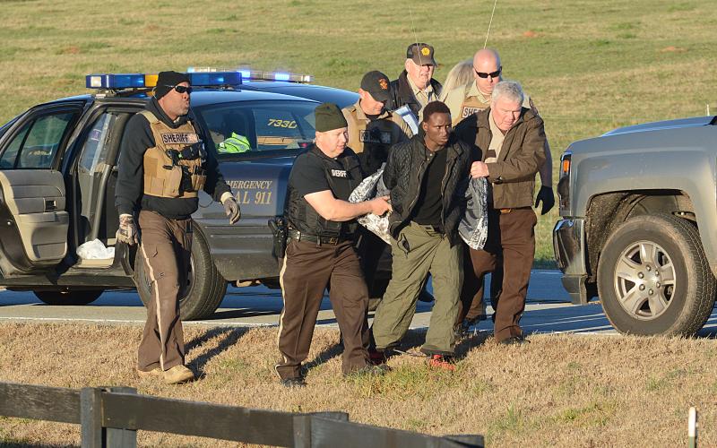 Hart County Sheriff's deputy David Cleveland (left) and Sheriff Mike Cleveland (right) escort murder suspect Larrendrick Rashad Tabor after his arrest Tuesday near South Hart Elementary School in Hart County. (Photo courtesy of The Hartwell Sun)