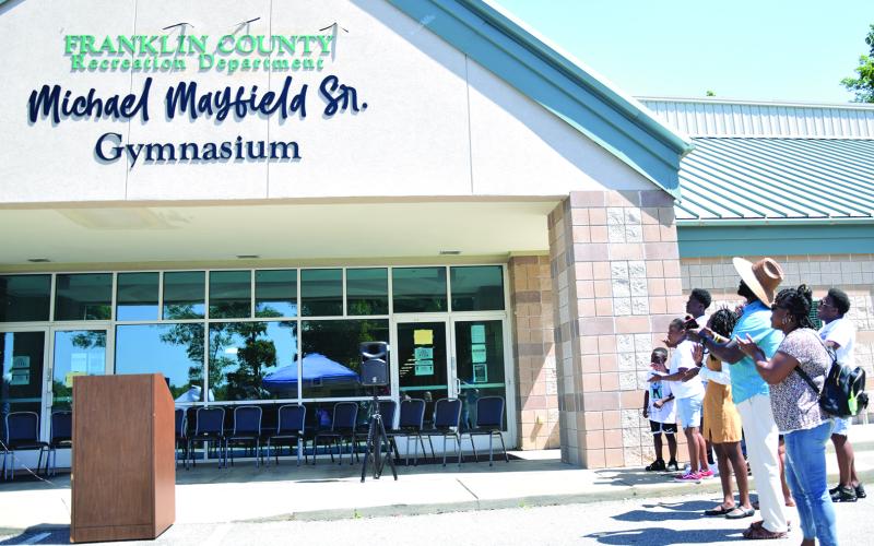 Members of the Mayfield family applaud after unveiling the sign proclaiming the new name of the gym at Rocky Ford Park as the Michael Mayfield Sr. Gymnasium. (Photo by Scoggins)