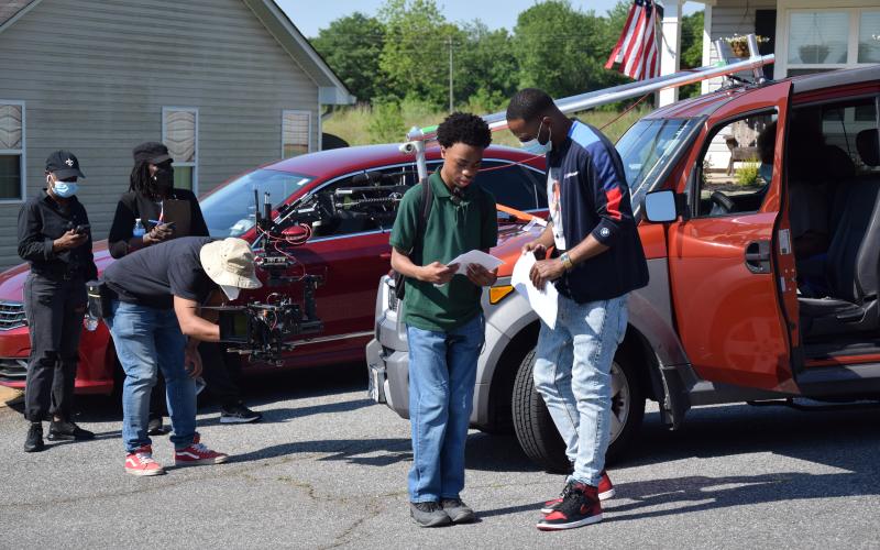Director David Nix Jr. (right) talks with an actor as crews set up a camera to shoot a movie scene Sunday in Crestview Heights in Carnesville. (Photo by Scoggins)