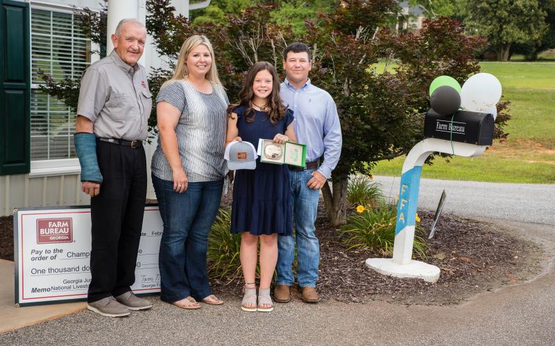 Carlie Christian was honored by the Franklin County Farm Bureau recently for winning the Georgia National Junior Livestock Show. At a ceremony at the Farm Bureau office in Carnesville, Carlie was presented a hat, a championship buckle and her prize money by Georgia Farm Bureau President Tom McCall. Carlie was joined by her parents Leslie and Bryan. Carlie has been a regular award winner in livestock shows and keeps her prizes on display at her home.