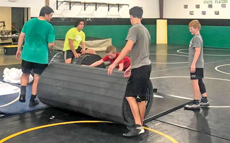 The wrestling team unrolls its new mat.