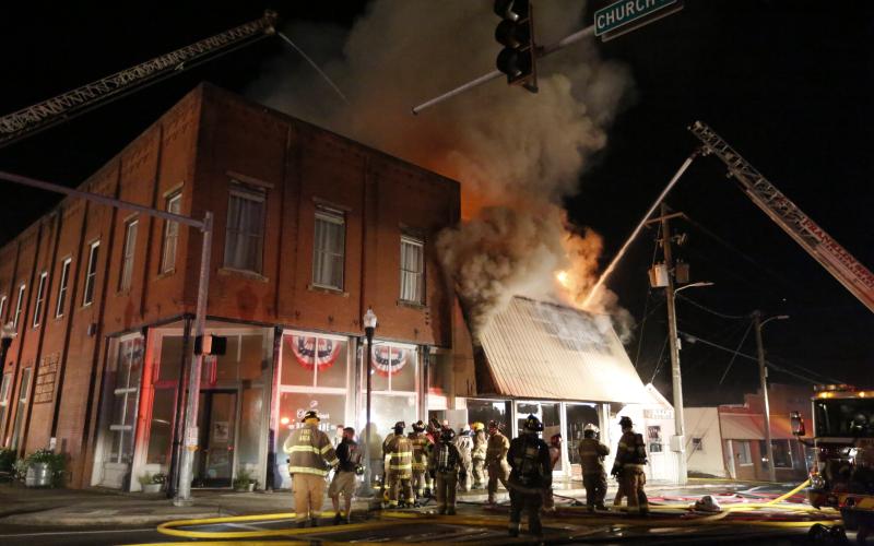Firefighters work to extinguish a fire Tuesday in the former Royce Theatre building in downtown Royston. The building was being used for storage at the time of the fire, which was contained to just that building. For more photos from the fire, see Pages 4-5A. (Photo by Rose Scoggins)