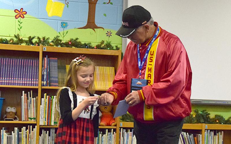 Toys for Tots Local Coordinator Mike Prather hands Bristol Patterson a Toys for Tots train pin to thank her for thinking of the organization during Carnesville Elementary School’s Pay It Forward project. (Photo by Sinclair)