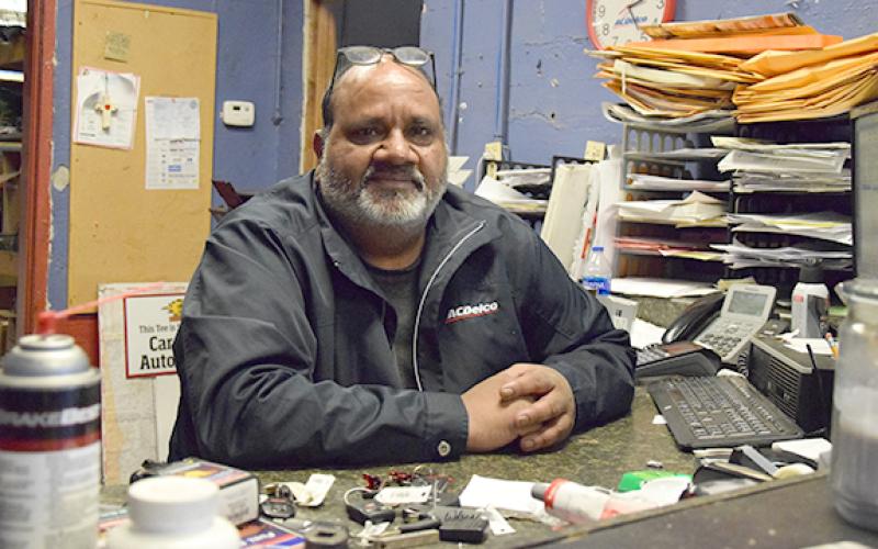 From behind his desk, Radha Sinha can hear customers come through the squeaky front door, and enjoys bringing smiles to their faces. He opened Car Point Automotive 20 years ago. (Photo by Sinclair)