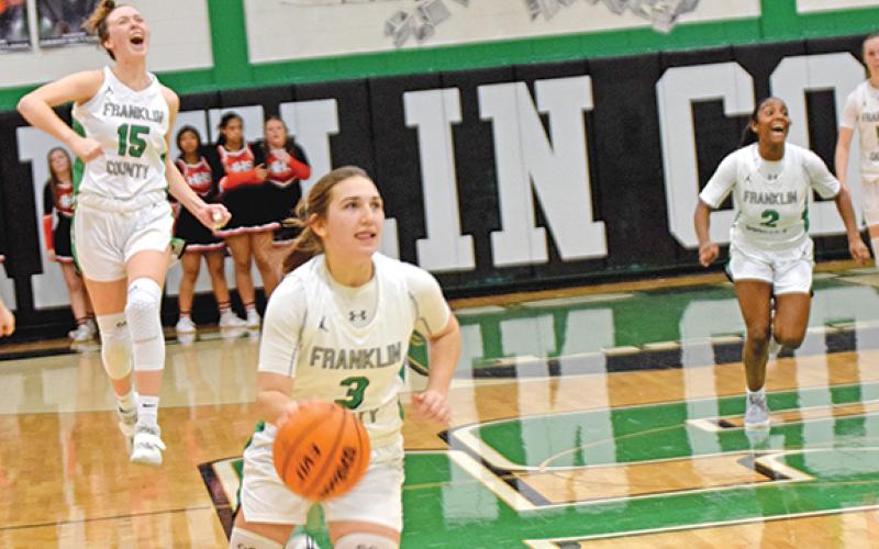 Kayleigh Chappell dribbles toward the basket as time runs out Friday night in the Franklin County Lady Lions’ overtime victory over Hart County in the Lions’ Den. Her teammates Emily Carson (No. 15) and Paris Gaye (No. 2) celebrate in the background. (Photo by Scoggins)