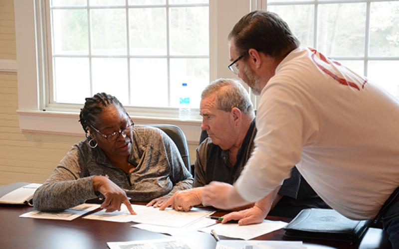 Carnesville council members Patsy Watkins, Mike Barrett and Wesley Dove go over plans for a 200-lot subdivision on 156 acres that developer Aubrey Lunsford has asked to be annexed into the Carnesville city limits. The council will vote on the proposal at its meeting April 5. (Photo by Scoggins)
