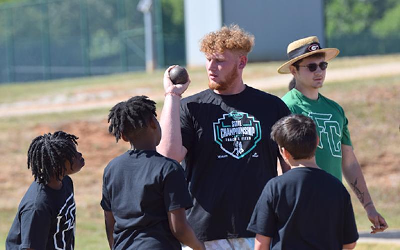 Keylan “Red” Rutledge, fresh off winning a AAA State Championship in shot put, gives pointers to future Lion athletes Tuesday during the Junior Olympics. (Photo by Scoggins)