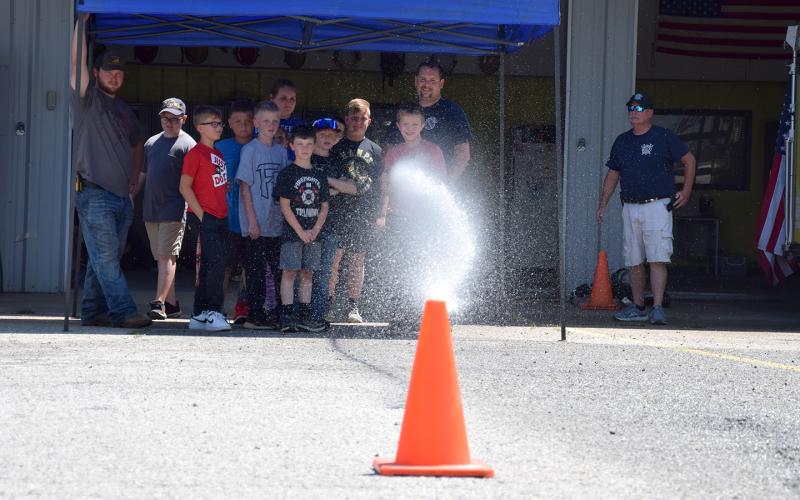 Mitchell Thurmond attempts to knock over a cone while using a fire hose during Junior Firefighter Day last week at the Carnesville Fire Department. (Photo by Sinclair)