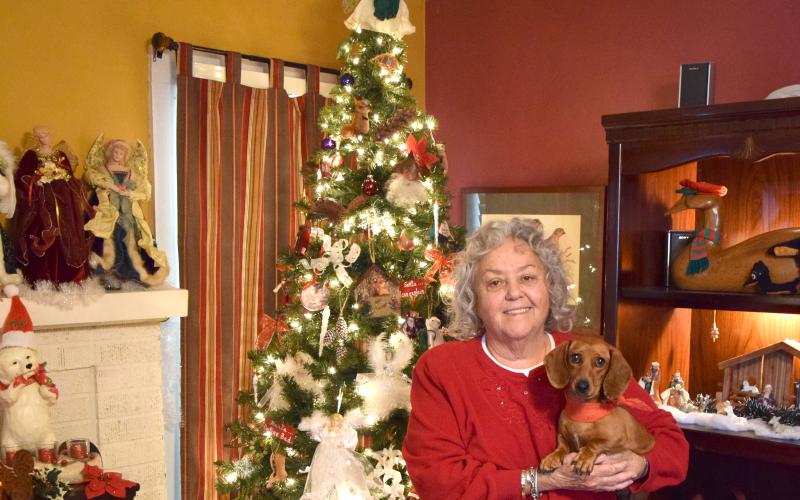 Marcia Millsap, with Duchess, stands in front of her Christmas tree, which is just one of the many decorations in her home. Millsap transforms the inside of her house each year into a holiday wonderland. For the complete story, see Page 12A. (Photo by Scoggins)