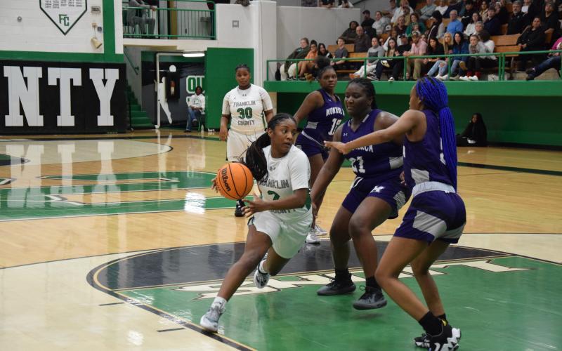 Paris Gaye drives by two Monroe defenders Tuesday in action at the Lion’s Den. Gaye had 23 points to lead the Lady Lions to a win.