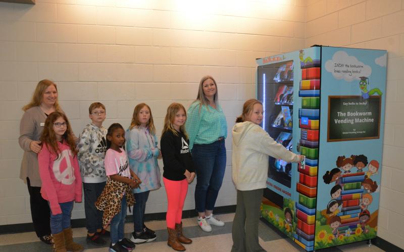 Students at Carnesville Elementary stand in line to try the new “Inchy” the Bookworm’s Book Vending Machine. The machines were recently placed in Carnesville, Royston and Lavonia Elementary Schools. The schools use the program as an incentive for the children to read more. Depending on the school, the rewards are based on behavior, attendance and/or grades. The eager readers are (from left) Freya Kolton, Will Cain, Jade Johnson, Keri Taylor and McKenna Carter. Looking on are (from left) Rita Shoemaker, dire