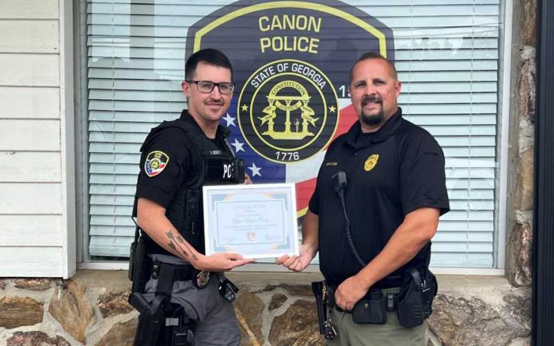 Canon Police Chief Brad Cook (right) presents Officer Austen Carey with a commendation for helping save a life after a recent accident.