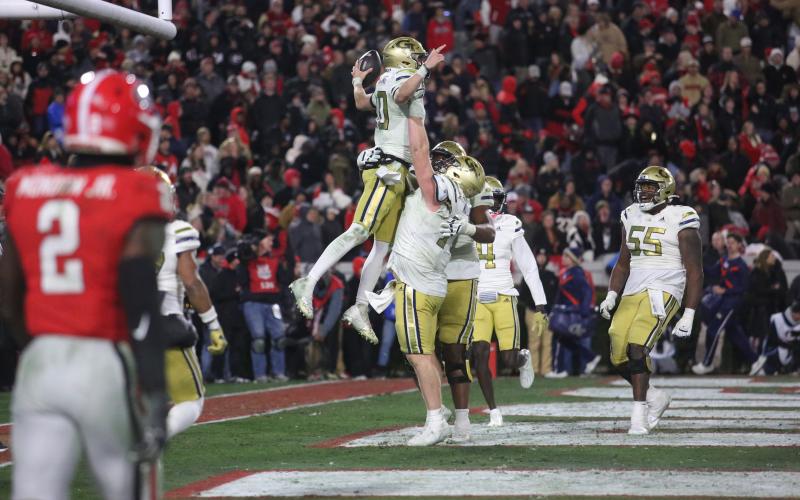 Keylan Rutledge lifts up Georgia Tech teammate and quarterback Haynes King after a touchdown against Georgia in Sanford Stadium. (Photo by Rose Scoggins)