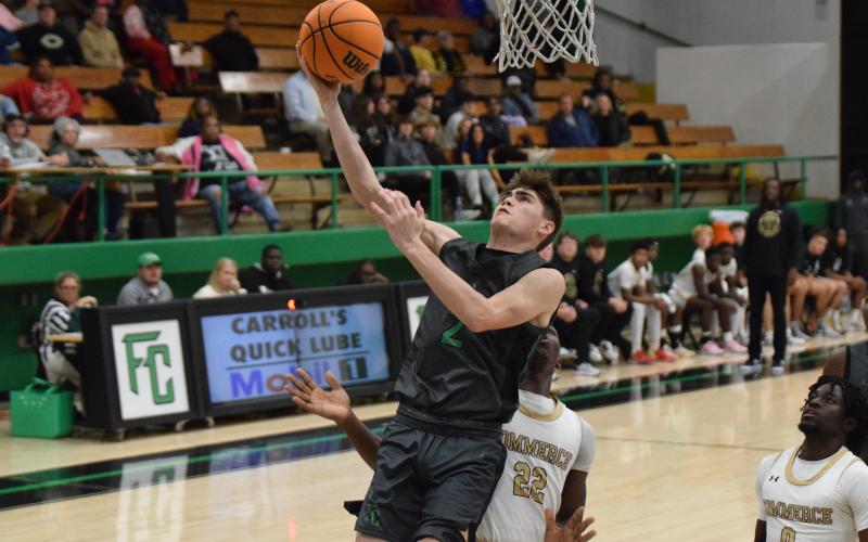 Carson Coulter goes in for a layup Thursday against Commerce in the Lion’s Den. (Photo by Scoggins)
