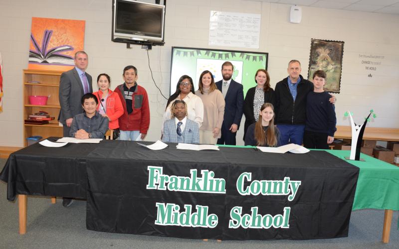 Franklin County Middle School held a signing ceremony Thursday for three students selected as REACH Scholars for the Class of 2029. Those in attendance were the REACH Scholars (seated from left) Khang Tran, Braylen Morrison and Selma Alicic, (standing, from left) FCMS Principal Dr. David Cawthon,; Trang Le and Kha Tran; Shanda Morrison; FCMS Assistant Principal Meredith Kilgore; FCMS Assistant Principal John David; and Mirzeta, Denis and Mirza Alicic. (Photo by Eavenson)