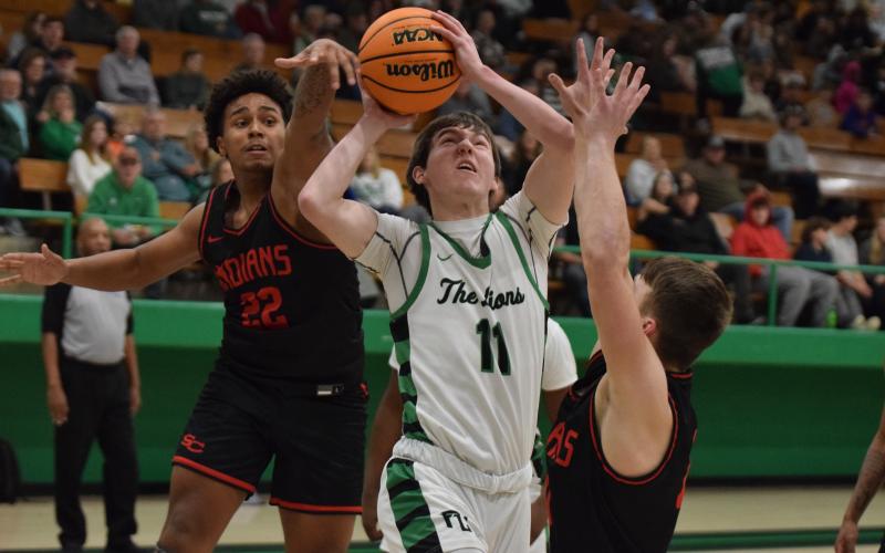 Bentley Huff goes up between two Stephens County defenders for a layup in Friday’s Franklin County Lion blowout of the Indians in Carnesville. (Photo by Scoggins)