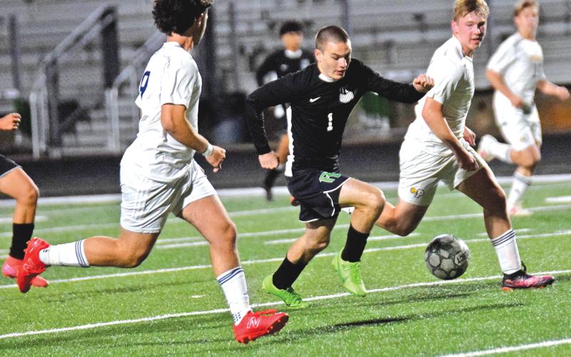 Lion Jonah Burger splits two Prince Avenue defenders on his way to a goal Friday night at Jeff Davis Field at Ed Bryant Stadium.