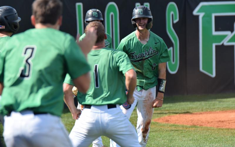 Franklin County teammates stream out of the dugout Saturday to celebrate with Mason Davis (No. 6), who scored one of the Lions’ 10 runs in a victory over East Jackson to clinch a berth in the second round of the state playoffs. (Photos by Scoggins)