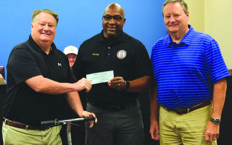 Tracy Dilworth (left) and Stan Dilworth (right) present a $100,000 check to Royston Mayor Keith Turman to go toward building a new water line on Cook Street. (Photo by Shane Scoggins)