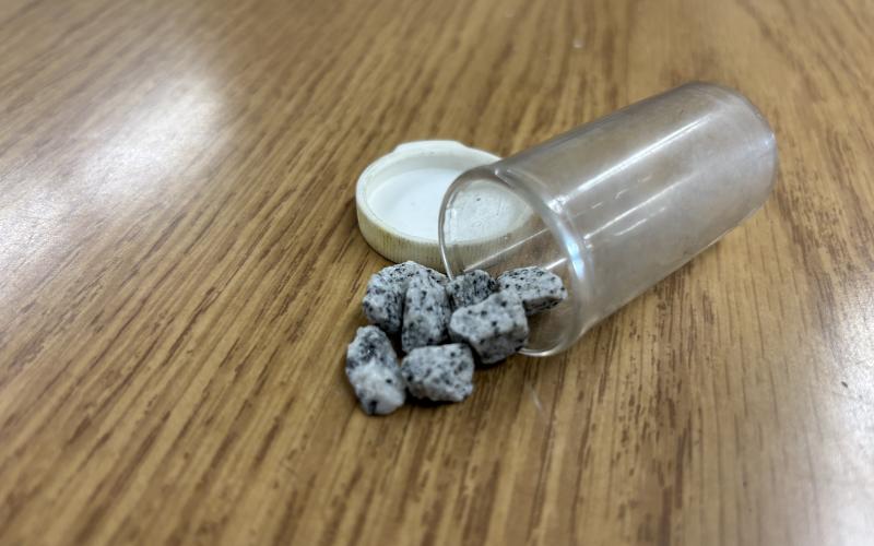 A small pill bottle containing eight pieces of gravel serve as a reminder that in local journalism, you will never see it all.
