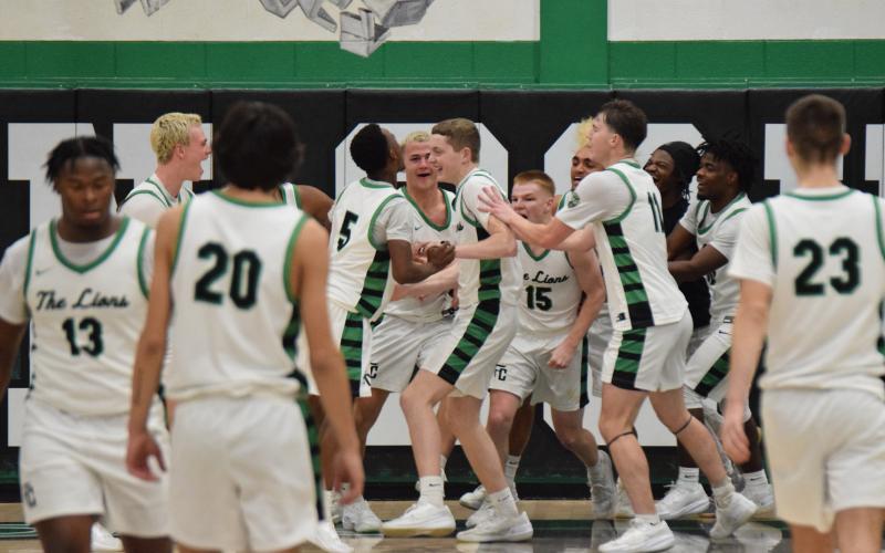 Teammates swarm Sam Shaver after the sophomore made a last-second shot to defeat Habersham Central Dec. 13 in the Lions’ Den. (Photo by Shane Scoggins)