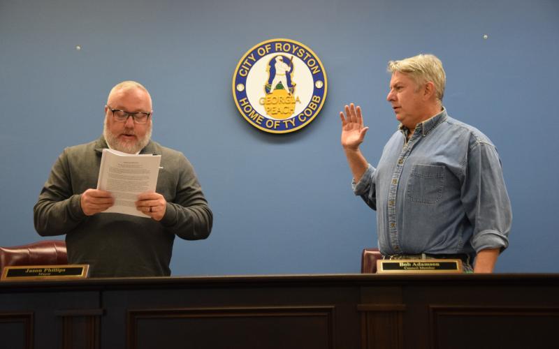 Royston Mayor Jason Phillips (left), presiding over his first meeting as mayor, swore in new Council Member Bob Adamson (right) as well as re-elected members Matt Fields and David Pressley (not pictured) during the Royston City Council’s meeting Tuesday at Royston City Hall. (Photo by Shane Scoggins)