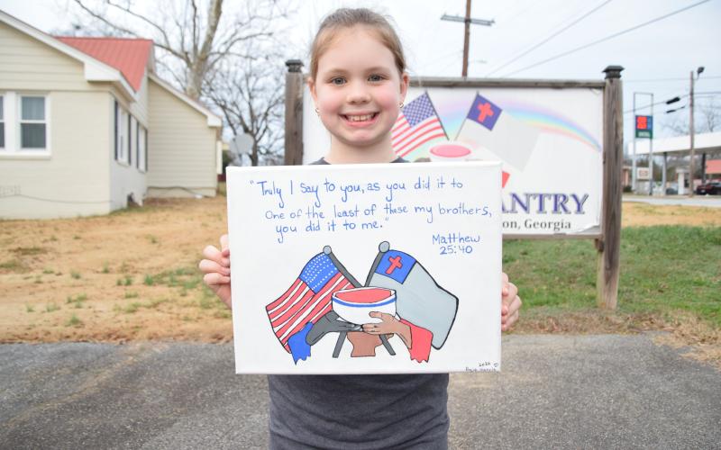 Posie Harris shows off an original painting of The Rainbow Pantry logo that she donated to the charity, along with proceeds from an auction of her other artwork. (Photo by Shane Scoggins)