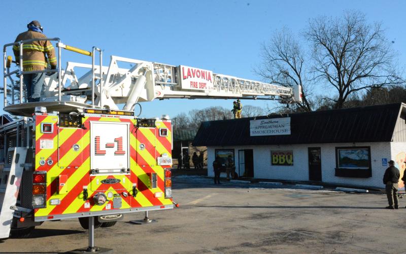 A ladder truck from the Lavonia Fire Department stretchs across to deposit firefighters on the roof of the Southern Applachian Smokehouse restaurant during a fire Tuesday. (Photos by Charlie Eavenson)