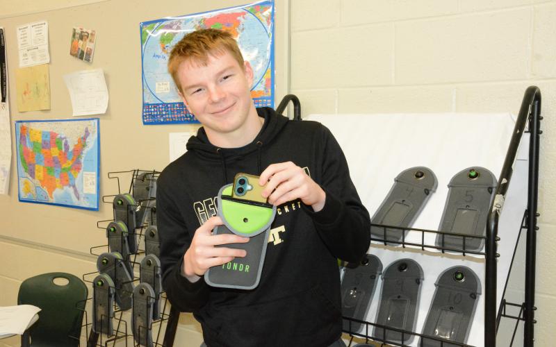 Hudson Huff (right photo), an FCHS student, demonstrates how the Yondr system works in one of the classrooms testing the program this year. (Photo by Charlie Eavenson)