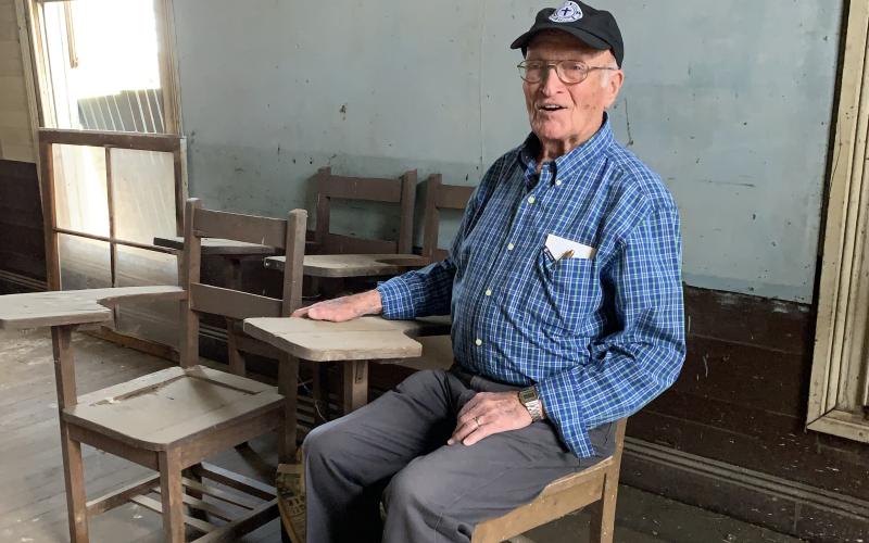 Retired pastor, and former Plainview School student, Isaac McDuffie takes a seat where he attended first grade in 1941. The 90-year-old said he had lots of fond memories from Plainview where he completed all seven grades. He stopped by during a planned work day Saturday. (Photo by Charlie Eavenson)