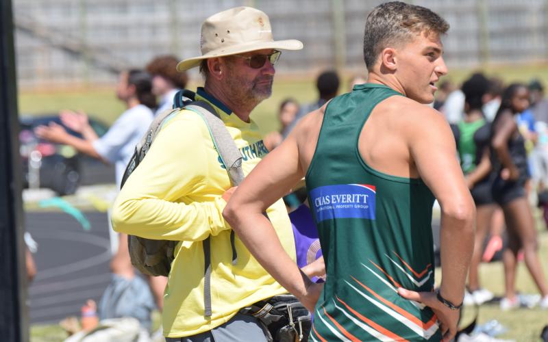 Coach Blackie Swart (left) and Dian Huisemen of Rustenburg High School in South Africa stand at the triple jump pit during Saturday’s John Scott Hartness Invitational track and field meet at Franklin County High School. (Photo by Shane Scoggins)