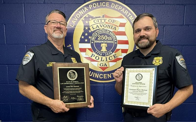 Lavonia Police Chief Shane Edmisten (left) and State Certification Manager Lt. Wayne Mitchum (right) show off the department’s recertification plaques the department earned.