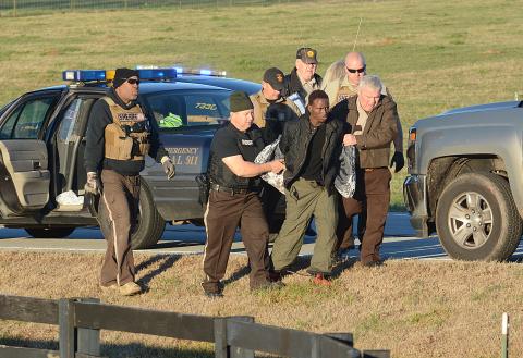 Hart County Sheriff's deputy David Cleveland (left) and Sheriff Mike Cleveland (right) escort murder suspect Larrendrick Rashad Tabor after his arrest Tuesday near South Hart Elementary School in Hart County. (Photo courtesy of The Hartwell Sun)