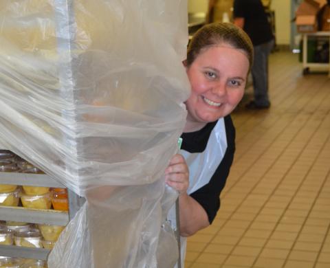 Michelle Jorschumb peeks from behind a cart as she and other members of the Lavonia Elementary School food nutrition service prepare to hand out meals Tuesday for students. (Photo by Eberhardt)