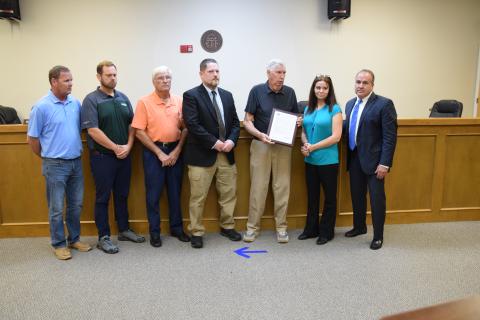 Franklin County Commissioners (from left) Eddie Wester, Ryan Swails, Robert Franklin, Jason Macomson and Chairman Thomas Bridges present Jennifer Garner, widow of Deputy William “Bill” Garner, with a plaque containing a resolution in her husband’s honor. Deputy Garner was killed July 19 in the line of duty. (Photo by Scoggins)