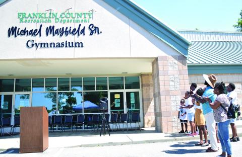 Members of the Mayfield family applaud after unveiling the sign proclaiming the new name of the gym at Rocky Ford Park as the Michael Mayfield Sr. Gymnasium. (Photo by Scoggins)