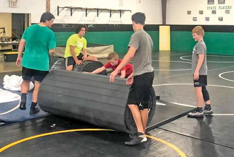 The wrestling team unrolls its new mat.