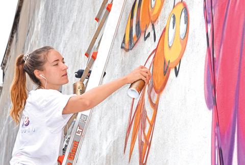 Kelly O’Brien paints a cartoonish scene of a flower welcoming bees. (Photo by Sinclair)