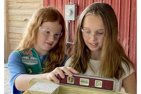 Girl Scout Juniors Kate Graham and Charlie Smith check to make sure the bench they are building is level.